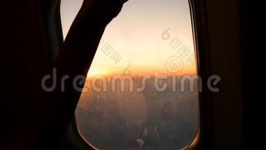 孩子打开飞机上窗户的百叶窗，看日落